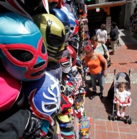 Masks hang over shoppers on Olvera Street during Cinco De Mayo festivities