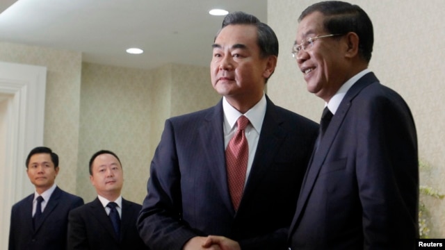 Chinese Foreign Minister Wang Yi (2nd R), shakes hands with Cambodia's Prime Minister Hun Sen before a meeting in Phnom Penh, Aug. 21, 2013. 
