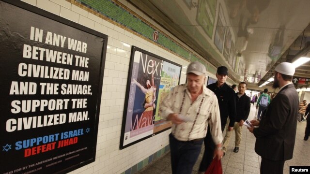 Cyrus McGoldrick, a member of the Council on American-Islamic Relations, talks to commuters as they walk by an advertisement that reads "Support Israel/Defeat Jihad" in the Times Square subway station in New York, September 24, 2012.