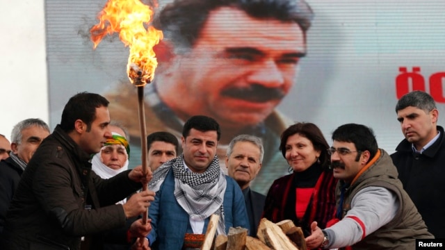 Selahattin Demirtas (front C), co-chairman of the pro-Kurdish Peace and Democracy Party (BDP), lights a traditional Newroz fire during a rally to celebrate the spring festival of Newroz - with a picture of imprisoned PKK leader Abdullah Ocalan seen in the