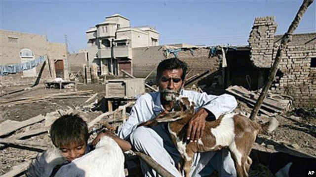 Flood survivor Kalo Jamali sits with his goats and a child in remains of his house destroyed by floods in the village Khairpur Nathan Shah, Pakistan, which is still surrounded by floodwaters, Nov 2, 2010
