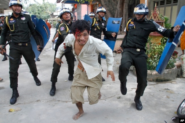 FILE - An injured worker escapes from riot police in the compound of a Buddhist pagoda in Phnom Penh, Cambodia, Nov. 12, 2013.