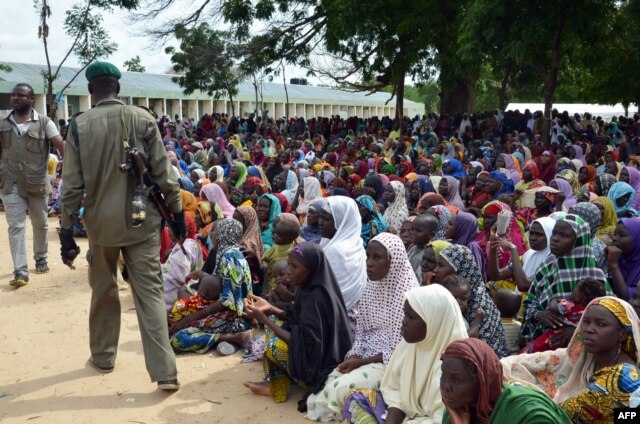 A policeman walks past dozens of people, who have been displaced from their communities after attacks by the Islamist group Boko Haram, at a camp for internally displaced people in Maiduguri, August 3, 2015.
