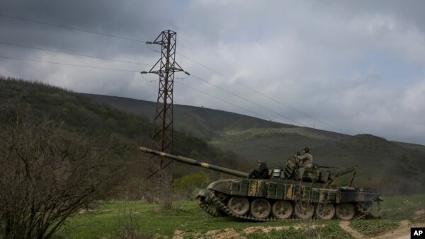 Armenian soldiers patrol on a tank near the village of Madaghis