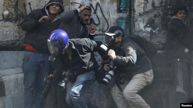 Photographers cower as protesters throw stones towards riot police along Sheikh Rihan street near Tahrir Square in Cairo January 25, 2013.