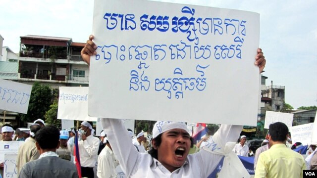 Một người biểu tình cầm biểu ngữ với dòng chữ "Có Sam Rainsy sẽ có bầu cử tự do và công bằng"