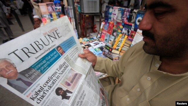 Một người đàn ông đọc tin về cái chết của thủ lĩnh Taliban Mullah Akhtar Mansour tại một sạp báo ở Peshawar, Pakistan, ngày 23 tháng 5 năm 2016.