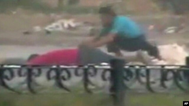A protester crouches near the body of a man lying on the ground in Hama in this still image taken from video posted on a social media website on August 4, 2011 (Reuters cannot independently verify the content of the video)