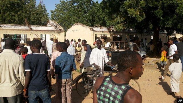 People inspect the damaged roof at the site of a suicide bomb explosion at the Government Science Technical College in Potiskum, Nigeria, Nov. 10, 2014.   