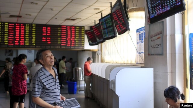 Nhà đầu tư nhìn vào bảng điện tử hiển thị thông tin chứng khoán tại một trung tâm giao dịch ở Thượng Hải.