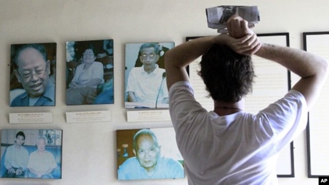 Tourist looks at portraits of former Khmer Rouge leaders Ieng Sary (R), 84, ex-foreign minister, his wife Ieng Thirith, 78, former minister of social welfare (2nd L), former prison chief Kaing Guek Eav (R), better known as Duch, former President Khieu Sam