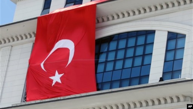 A Turkish flag is hung from the headquarters of Turkish Prime Minister Recep Tayyip Erdogan’s ruling party, apparently to conceal the damage after assailants fired a rocket on the building, in Ankara, March 20, 2013.
