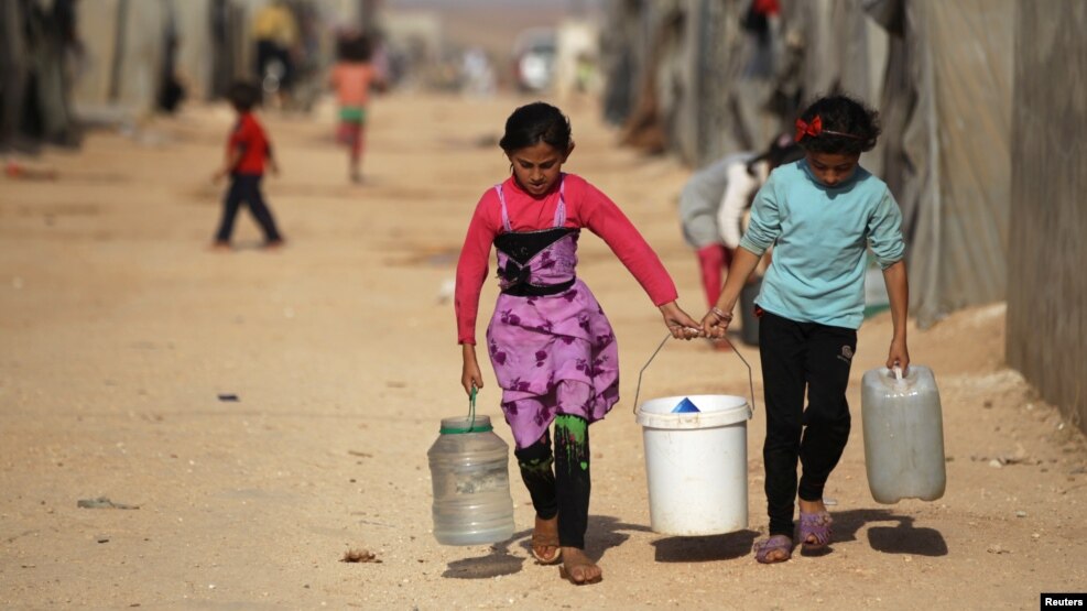 Internally displaced Syrian girls carry water containers in Jrzinaz camp in the southern part of Idlib, Syria, June 21, 2016.