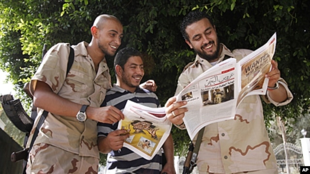 Anti-Gadhafi fighters read a newspaper where a wanted poster for Moammar Gadhafi was published in Tripoli September 1, 2011.