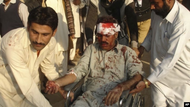 A man injured by a bombing in Dera Ghazi Khan is helped by local residents, 15 Dec 2009