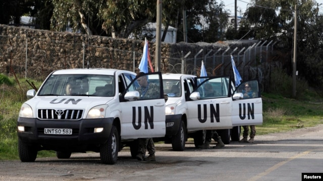 United Nations peacekeepers put on protective gear before driving through the Kuneitra border crossing between Israel and Syria, in the Israeli occupied Golan Heights, March 8, 2013.