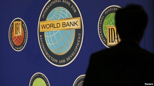 A man is silhouetted against the logo of the World Bank at the main venue for the International Monetary Fund (IMF) and World Bank annual meeting in Tokyo, October 10, 2012. 