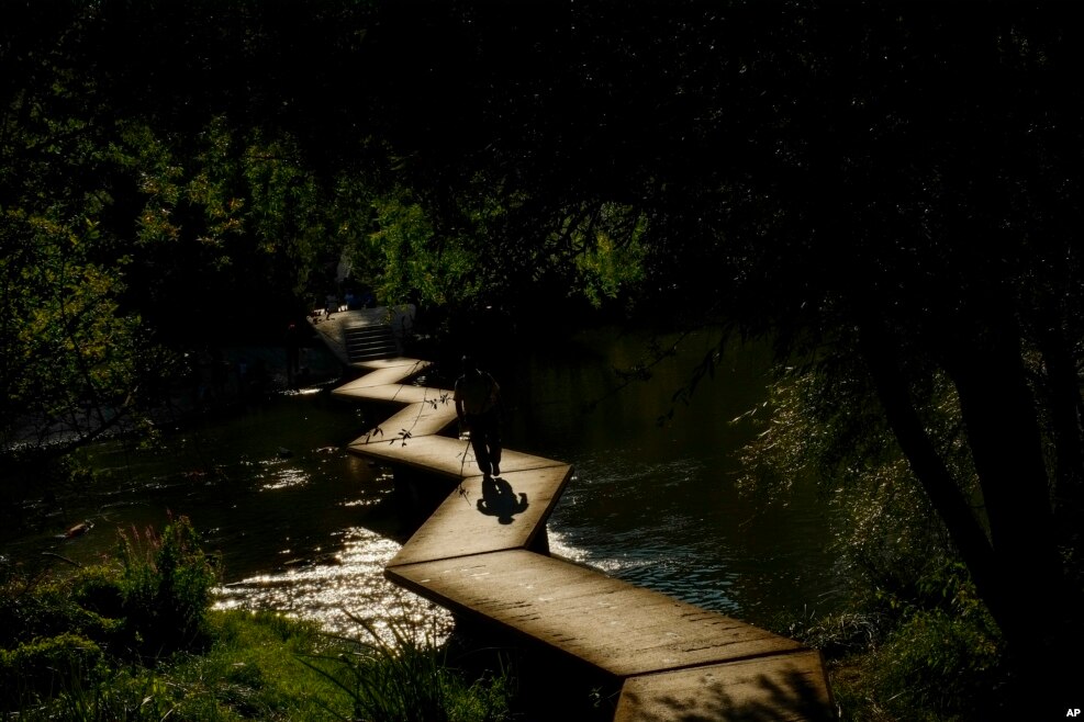 27일 스페인 북부 팜플로나를 흐르는 아르가강 위로 석양이 지는 가운데 한 남자가 다리를 건너고 있다.