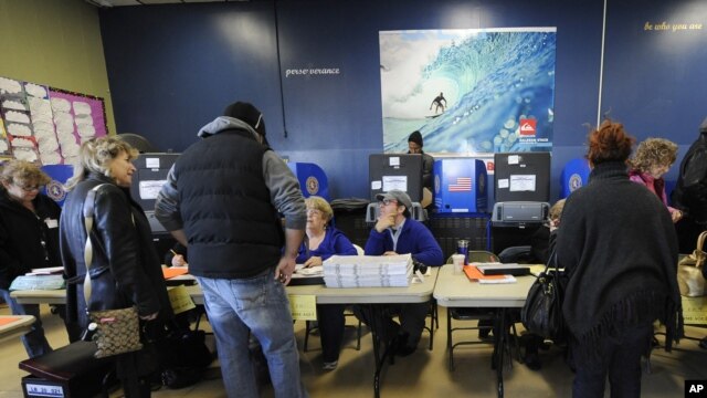 Voters sign in to vote at busy polling station at East Elementary School early Tuesday, November 6, 2012, in Long Beach, N.Y., one of several voting locations that were created as a result of Superstorm Sandy. 