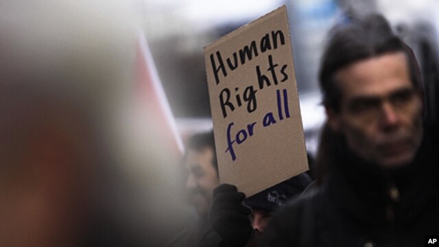 A protester holds a poster during a demonstration against racism and for human right for all people at the International Human Rights Day in Berlin,  Dec. 10, 2011.
