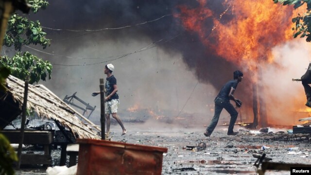 Rohingya men are seen among houses set on fire during fighting between Buddhist Rakhine and Muslim Rohingya communities in Sittwe, Burma, June 10, 2012.