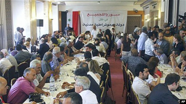 Prominent opposition figures and critics of Syrian President Bashar al-Assad's regime gather for a meeting, with attached banner in Arabic that reads 'Syria is for everybody, in the shadow of a democratic civil state,' in Damascus, Syria, June 27, 2011