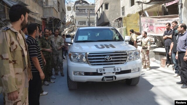 Binh sĩ thuộc Quân đội Syria Tự do vây quanh đoàn xe của các thanh sát viên LHQ đến điều tra về vấn đề vũ khí hóa học ở ngoại ô Zamalka, ngày 28/8/2013. 