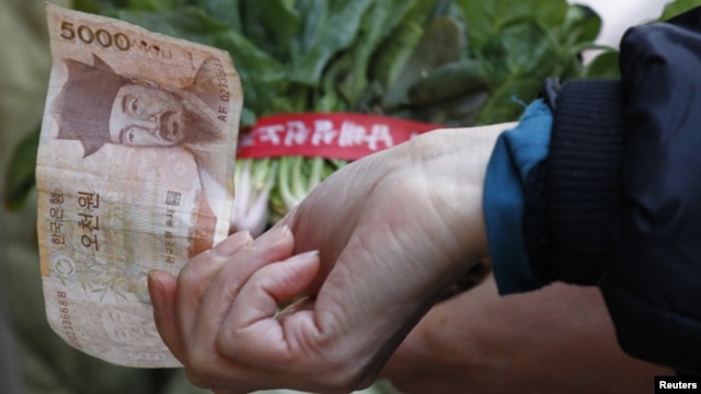 South Korean housewife buys vegetables at a market in Seoul February 1, 2011. 