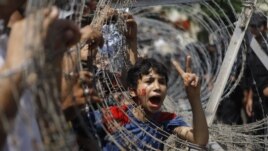 An Egyptian boy peers out of barbed wire during a protest in front of the Supreme Constitutional Court in Cairo, Egypt, Thursday June 14, 2012.