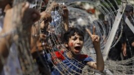 An Egyptian boy peers out of barbed wire during a protest in front of the Supreme Constitutional Court in Cairo, Egypt, Thursday June 14, 2012.