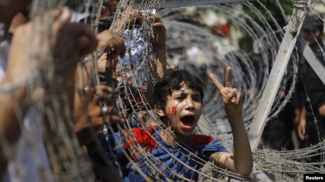 An Egyptian boy peers out of barbed wire during a protest in front of the Supreme Constitutional Court in Cairo, Egypt, Thursday June 14, 2012.
