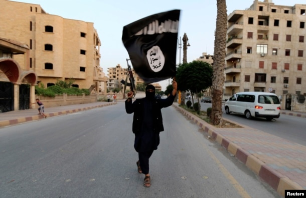 A member of the Islamic State carries the militant group's signature black flag in Raqqa, Syria in 2014.