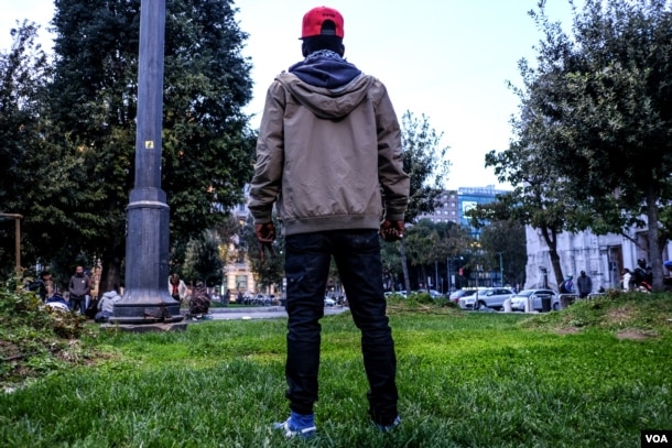 A migrant from Gambia poses while hiding his identity at Milan Central Train Station, Oct. 12, 2016. He, along with several other Gambian migrants, sleep outside at the station.(R. Shryock/VOA)