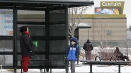 A woman and her grandson wait for a bus, near the fenced-in Century movie theater, the site of the deadly 2012 shootings, in Aurora, Colorado, January 15, 2013.