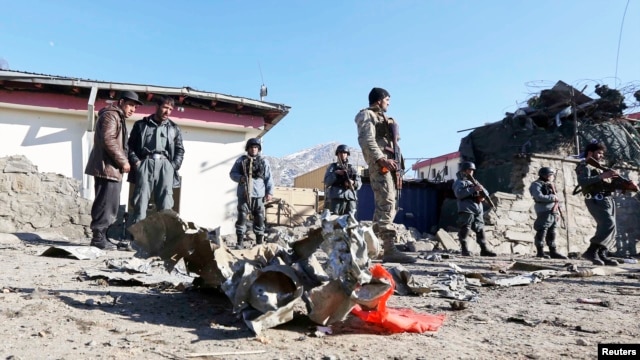 Afghan policemen stand guard at the site of an attack by insurgents against the Kabul traffic police headquarters in Kabul, Jan. 21, 2013.