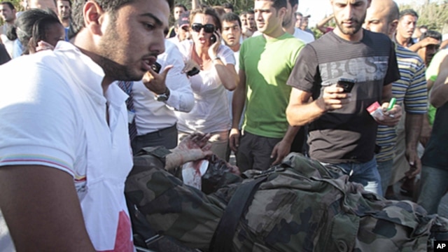 A Lebanese red cross worker, left, takes an injured French U.N. peacekeeper into an ambulance after a bomb explosion targeted a convoy of French soldiers in the southern port city of Sidon, July 26, 2011