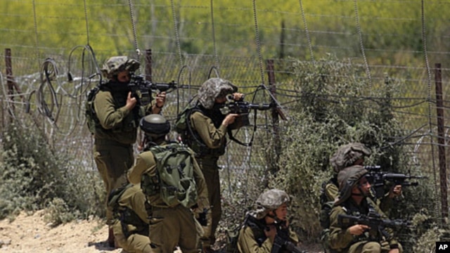 Israeli soldiers take aim next to the Syrian-Israeli border fence near the Druze village of Majdal Shams in the Golan Heights, June 5, 2011