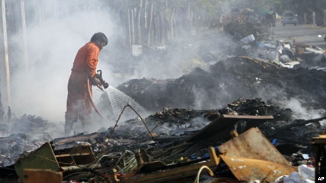 A firefighter puts out a fire on a pile debris left behind after flood waters, one of Thailand's worst floods in five decades, receded in Bangkok, January 6, 2012.