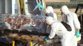 In this photo provided by the Spanish Defense Ministry, aid workers and doctors transfer Miguel Pajares, a Spanish priest who was infected with the Ebola virus while working in Liberia, from a plane to an ambulance as he leaves the Torrejon de Ardoz milit