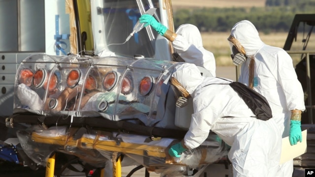 In this photo provided by the Spanish Defense Ministry, aid workers and doctors transfer Miguel Pajares, a Spanish priest who was infected with the Ebola virus while working in Liberia, from a plane to an ambulance as he leaves the Torrejon de Ardoz milit