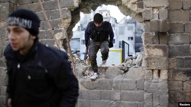 Free Syria Army fighters move through a hole in a wall during a fight with forces loyal to President Bashar al Assad at the front line in Aleppo December 24, 2012.