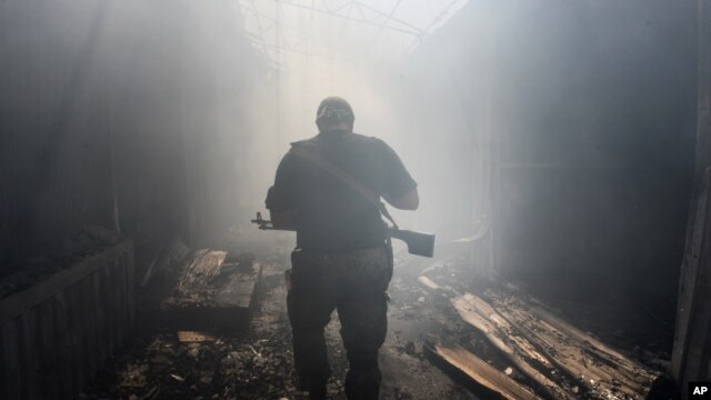 Một phần tử nổi dậy thân Nga đi trong khu chợ bị nã pháo ở quận Petrovskiy, thị trấn Donetsk, miền đông Ukraine, 26/8/2014.