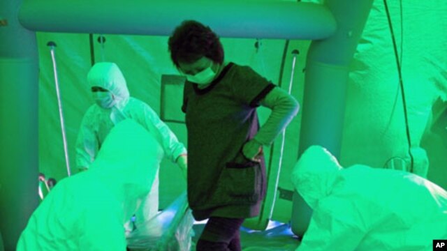 Medical staff use a Geiger counter to screen a woman for possible radiation exposure after she was evacuated from an area within 20 km radius of the Fukushima Daiichi nuclear plant, at a public welfare center in Hitachi City, Ibaraki, March 16, 2011
