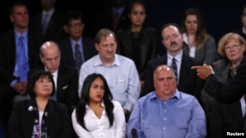 Members of the audience look on as U.S. President Barack Obama (R) speaks as he debates Republican presidential nominee Mitt Romney during the second U.S. presidential debate in Hempstead, New York October 16, 2012.