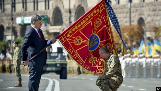 Tổng thống Ukraine Petro Poroshenko trao quốc kỳ cho một đơn vị quân sự trước cuộc diễu hành kỷ niệm ngày Quốc khánh của Ukraina ở thủ đô Kiev.