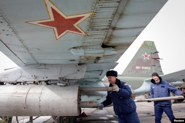FILE - Servicemen load air-to-ground missiles onto a Sukhoi Su-25 jet fighter during a drill at the Russian southern Stavropol region, March 12, 2015.