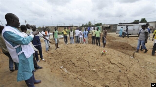 An Ivorian Red Cross worker photographs an area claimed to be a mass grave on May 4, 2011 during a mission to collect corpses in Yopougon, a district to the west of Abidjan.