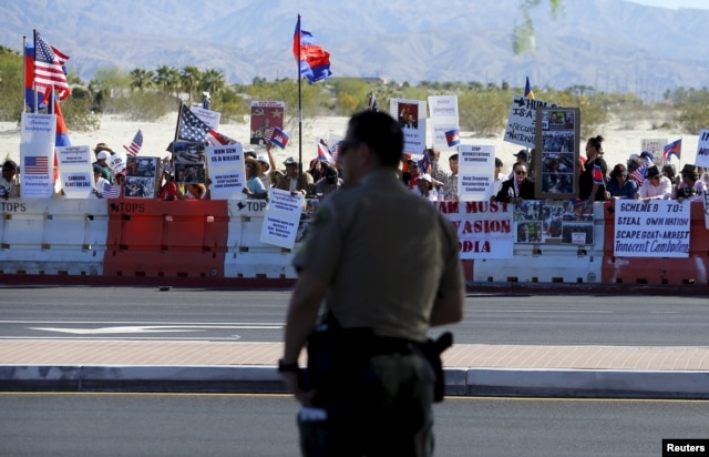 A police officer looks on as protesters line one side of a roadway leading to Sunnylands where U.S. President Obama prepares to host leaders from Southeast Asia at the ASEAN Summit in Rancho Mirage, California, Feb. 15, 2016.
