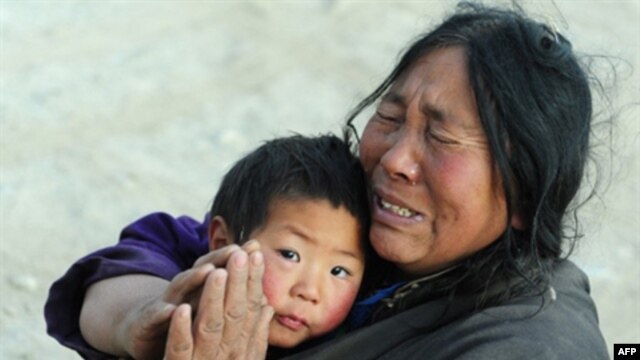 An earthquake survivor gestures in prayer while holding onto her nephew. (file)