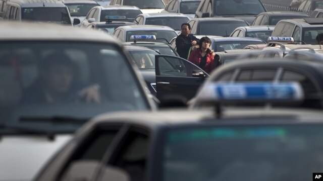 Motorists come out from their vehicle to check as the traffic stand still at a city road in Beijing, China, Tuesday, Nov. 22, 2011.